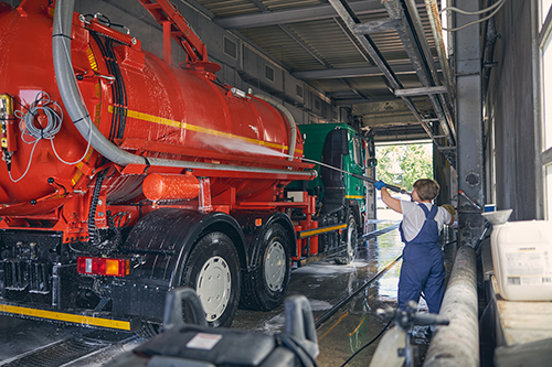 Serious woman standing in front of big transport and pouring down water on the special transport